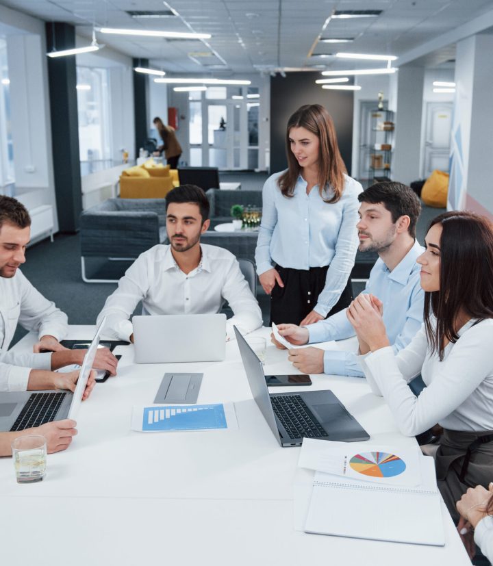 Guy on the left side talking and colleagues is listening to him. Group of young freelancers in the office have conversation and smiling Guy on the left side talking and colleagues is listening to him. Group of young freelancers in the office have conversation and smiling.